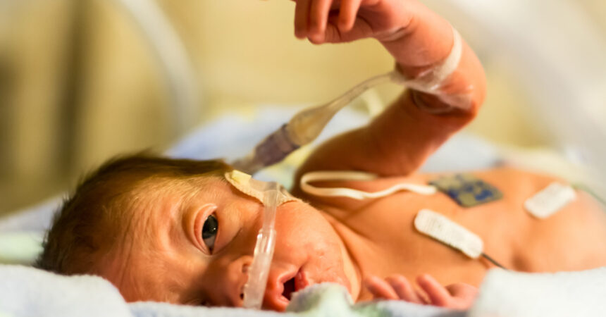 Preemie baby girl pointing in her incubator AdobeStock_141820489-scaled.jpeg